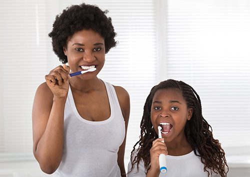 A mom and daughter brushing their teeth