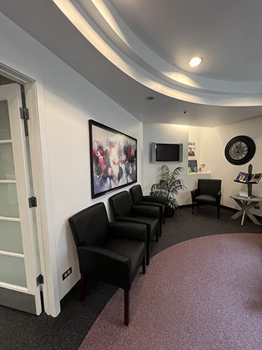 Welcoming patient waiting area with comfortable chairs, artwork, and a wall-mounted TV at Belleview Dental.
